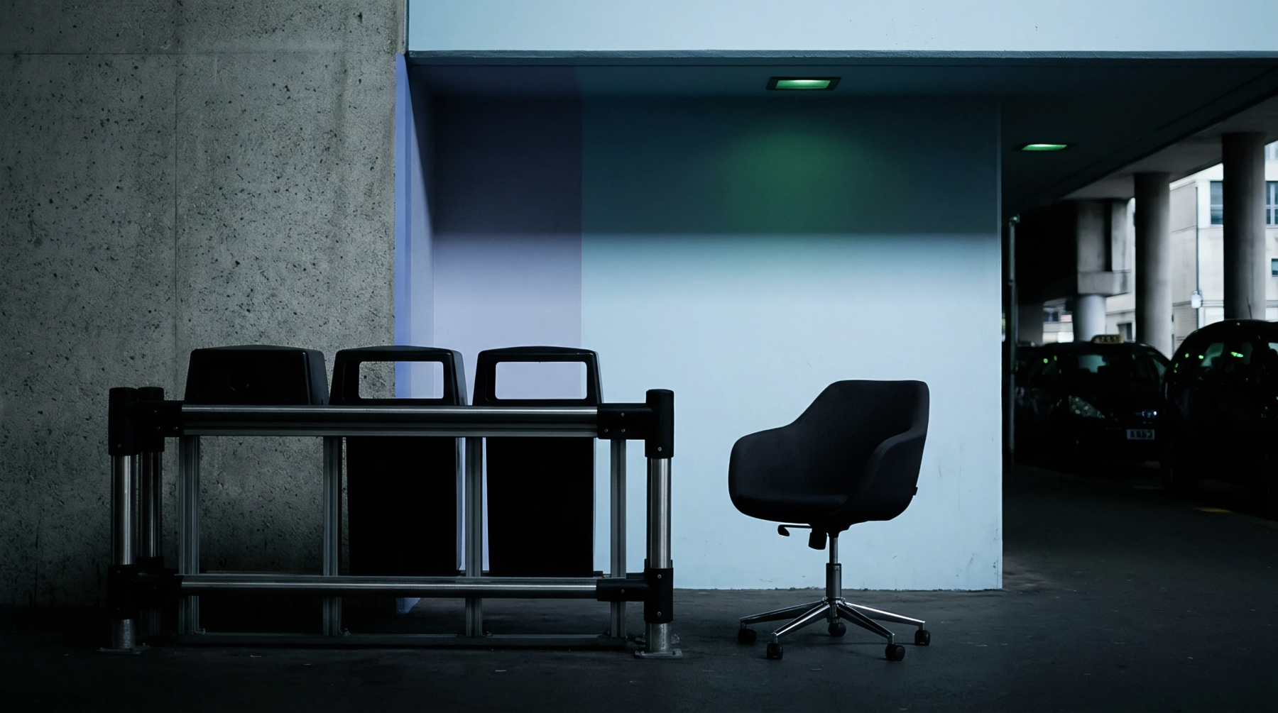 Cast metal equipment housing frames stand beside an ergonomic polyurethane task chair inside a concrete manufacturing facility extension zone.