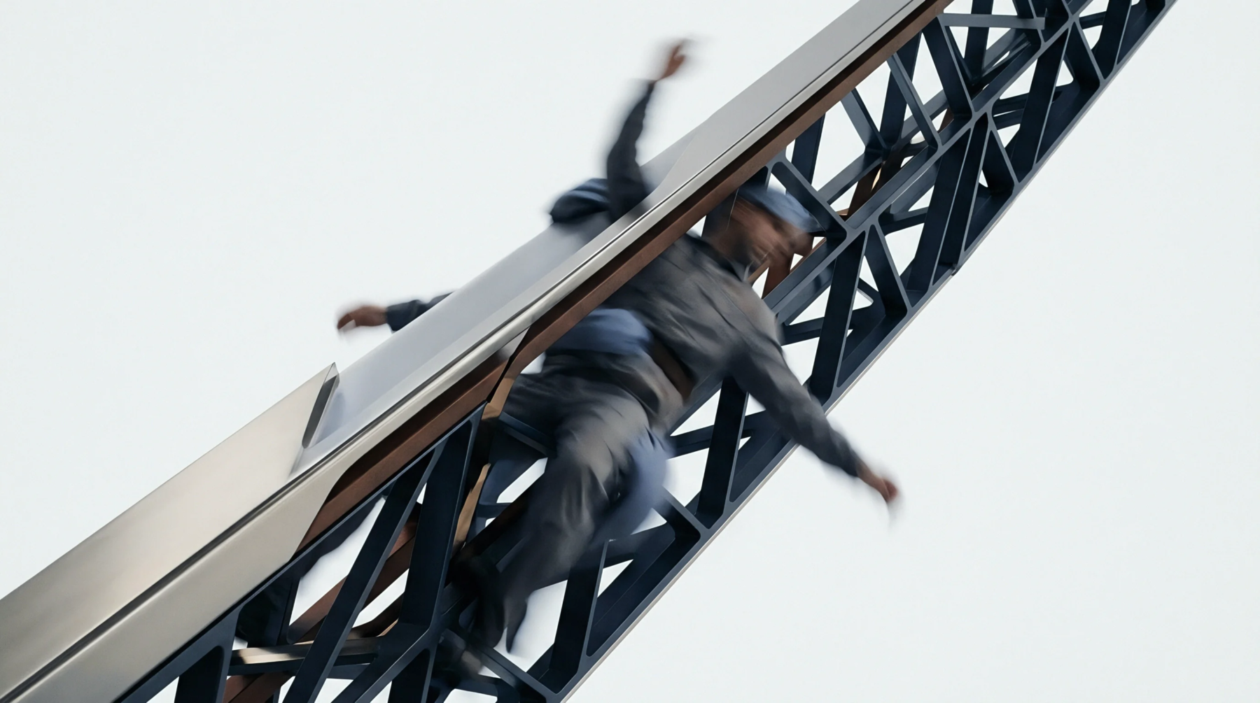 An individual descends rapidly along a steel framework truss system representing the inherent dangers and vulnerabilities found within high output industrial production sites.